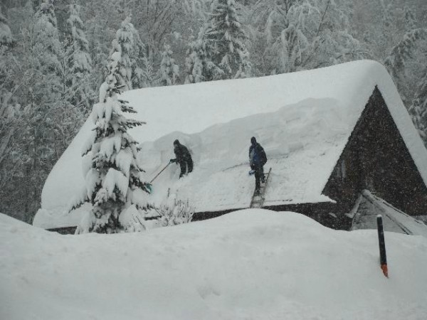 Privatpersonen beim Abschaufeln eines Hausdaches
