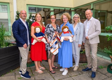 (v.l.n.r.) Direktor Wolfgang Friessenbichler, Wohnbereichsleiterin Bianca Giefing, Wohnbereichsleiterin Irene Rameder, Landesrätin Christiane Teschl-Hofmeister, Geschäftsführerin der Gesundheit Thermenregion Silvia Bodi und Vorstand NÖ LGA Konrad Kogler. Ebenfalls am Bild die sogenannten „Demenzpuppen“, die betroffenen Bewohnerinnen und Bewohnern im Alltag helfen.