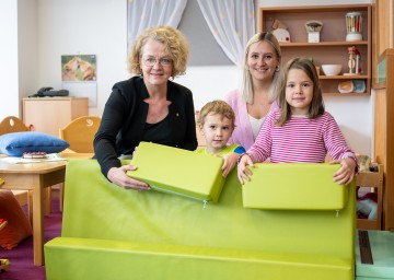 (v.l.n.r.): Familien-Landesrätin Christiane Teschl-Hofmeister und Pädagogin Carina Kerschner imitieren mit Simon Effenberger und Josephine Grießler mit Schaumstoffpolster einen Hochwasserschutz.