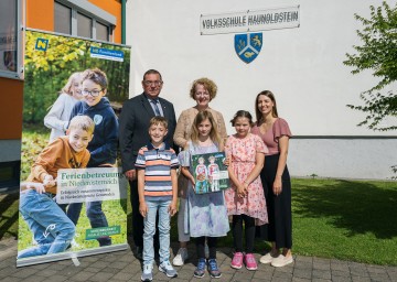 Bürgermeister Hubert Luger, Landesrätin Christiane Teschl-Hofmeister, die Betreuerin Jana Lackner (v.l.n.r.) und Kinder der Musikvolksschule Haunoldstein bei der Präsentation der diesjährige Ferienbetreuung in Niederösterreich.